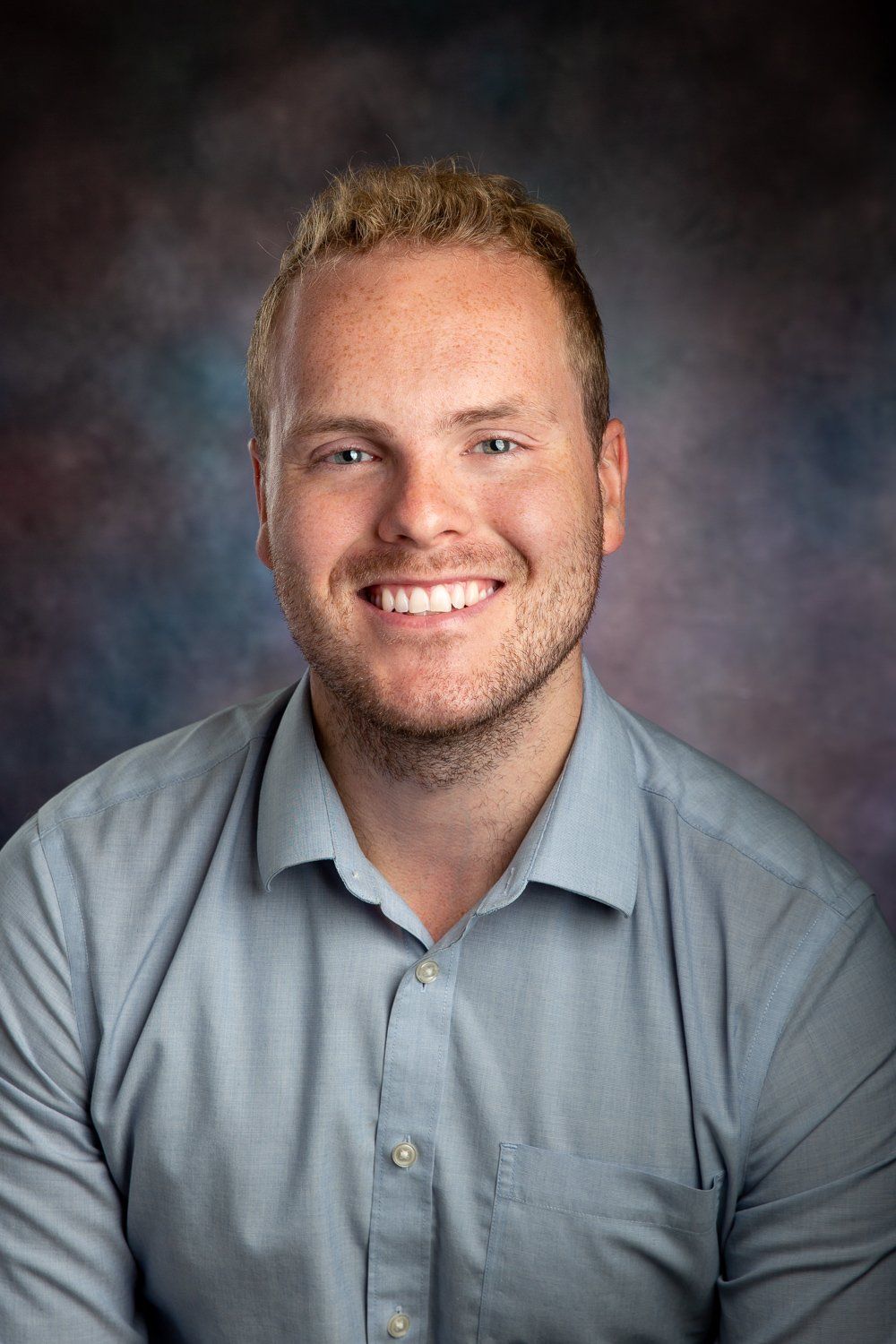A man in a blue shirt is smiling for the camera.