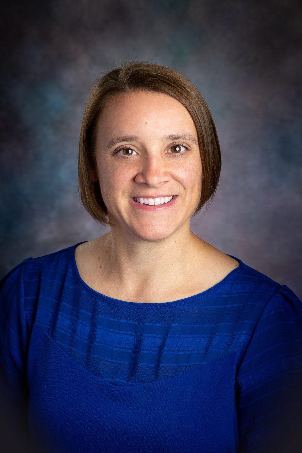 A woman in a blue dress is smiling for the camera.