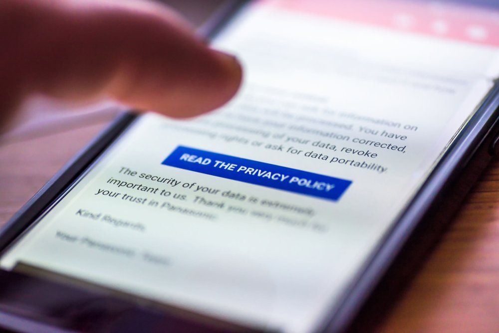 A person is pressing a button on a cell phone that says read the privacy policy