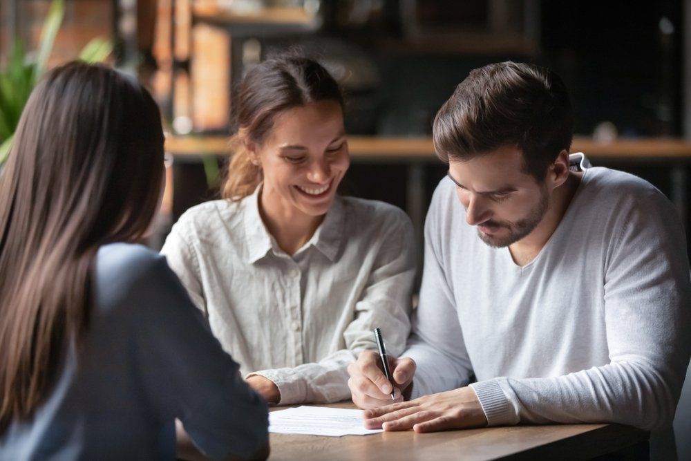 A man and a woman are sitting at a table signing a document.
