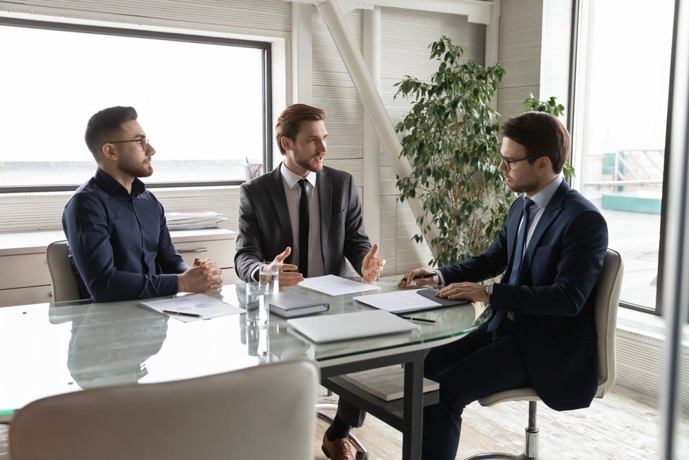 Three men are sitting at a table having a meeting.