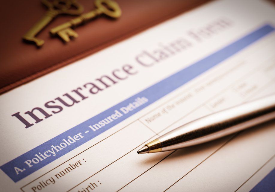 Insurance claim form with pen, keys, and a leather notebook.