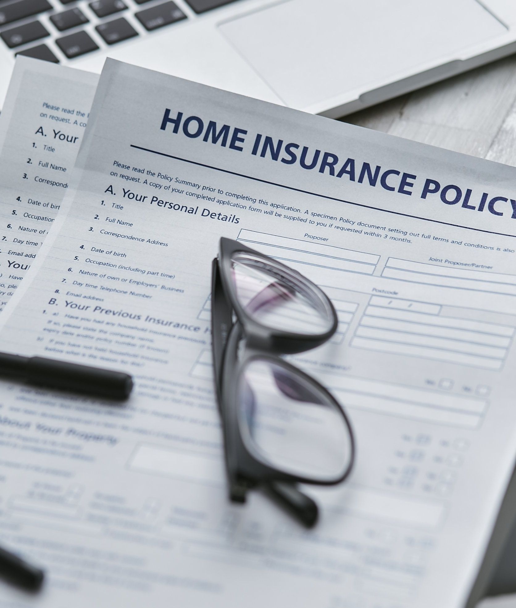 Home insurance policy document with eyeglasses resting on top.