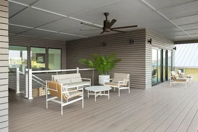 Outdoor patio with seating: sofa, chairs, round table, potted plant, and ceiling fan.