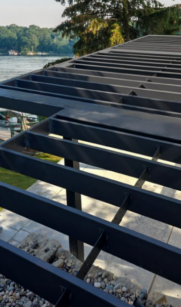 Black metal pergola with a lake view in the background.