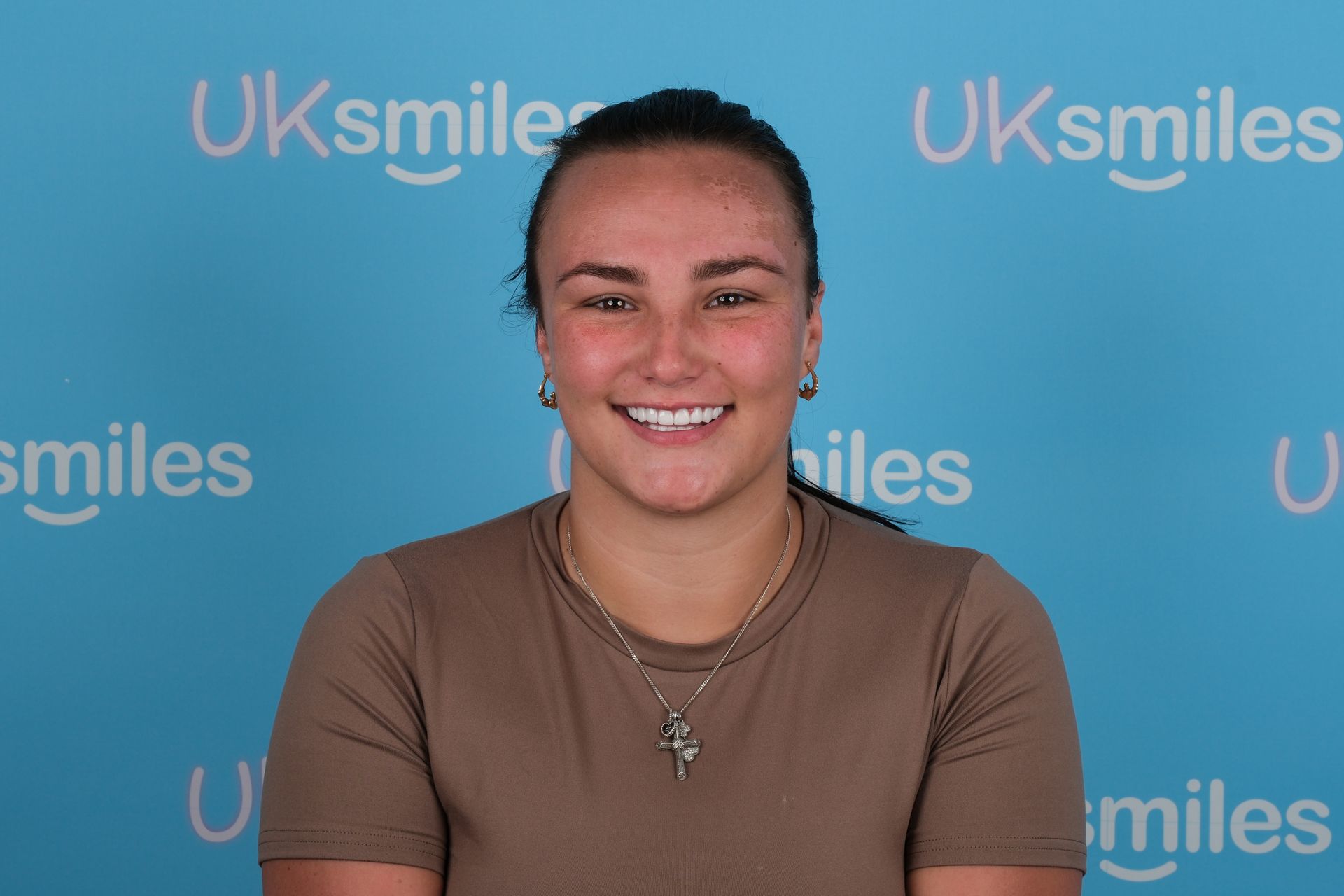Woman with a missing front tooth smiles at the camera; blue background with