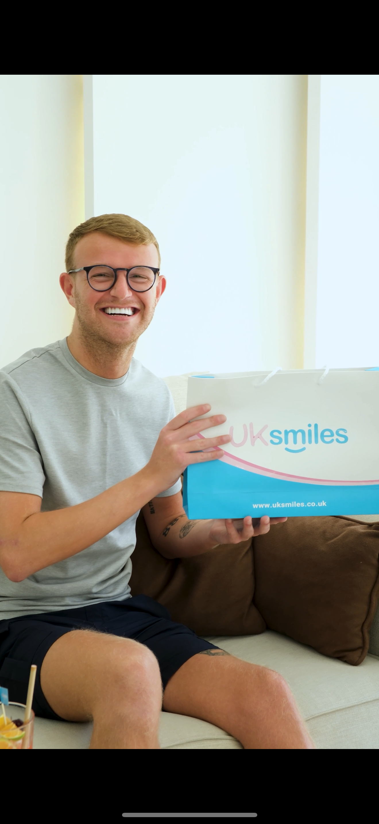 Man with glasses smiles, holding a box with