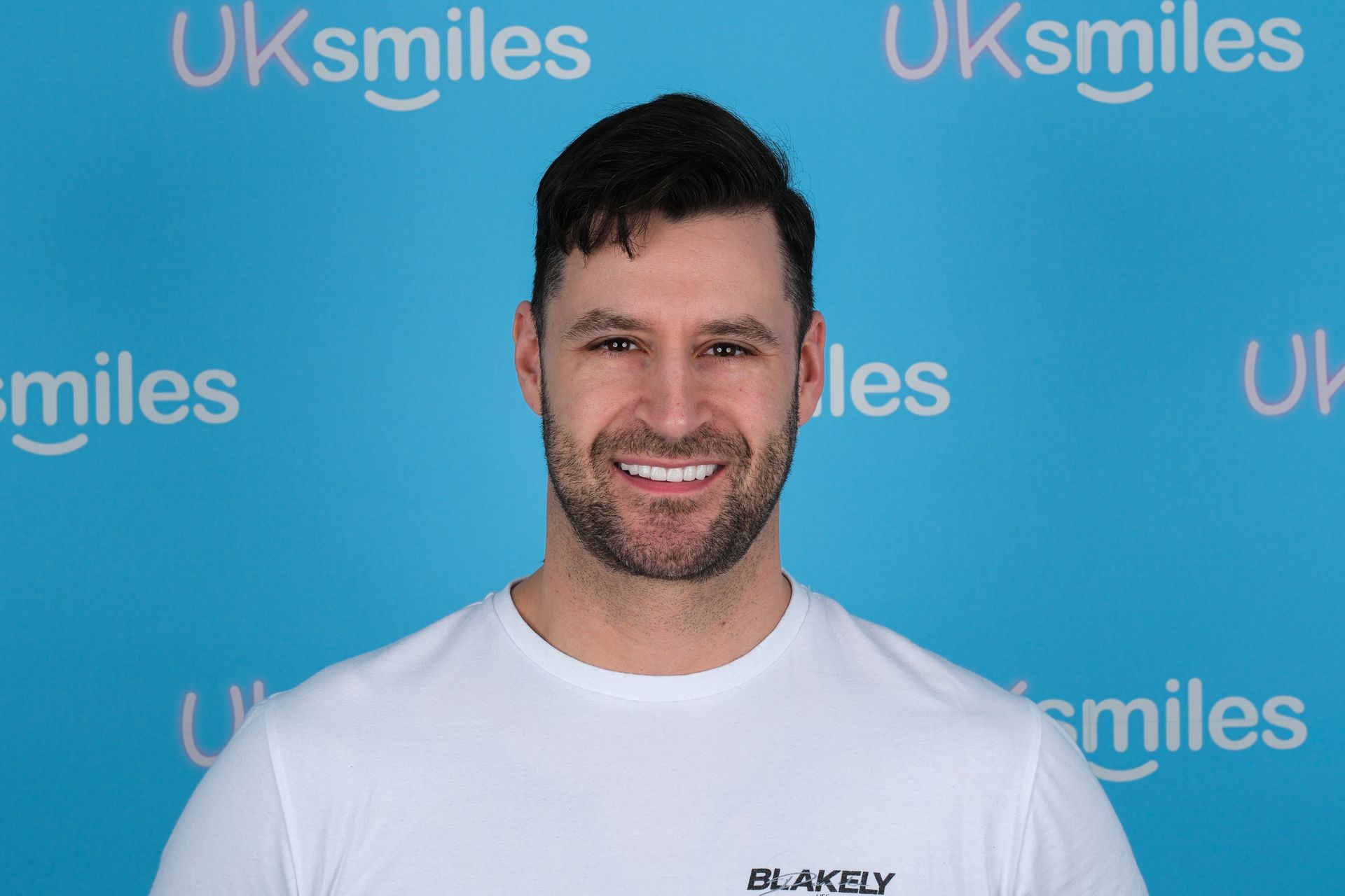 Man smiling with perfect white teeth against a blue background with