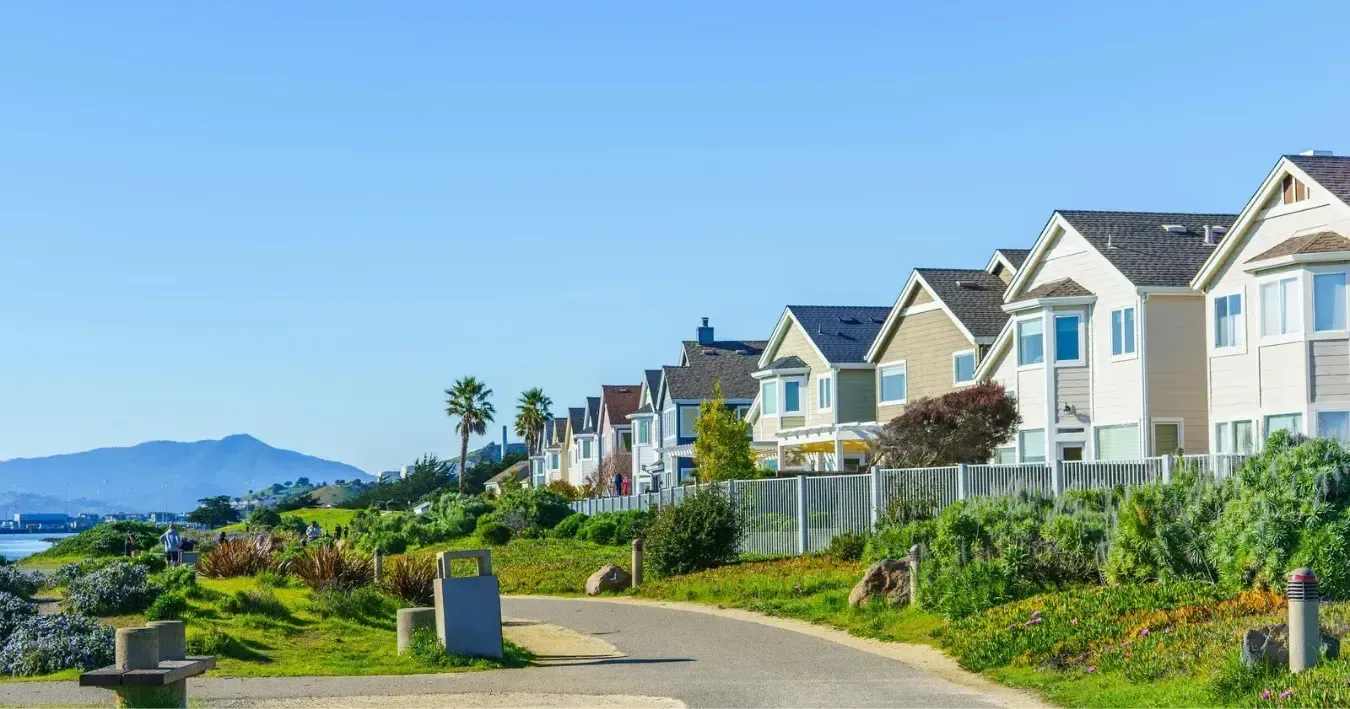 Sunny seaside neighborhood with row of blue-and-white houses beside a winding path and ocean view Sunny seaside neighborhood with row of blue-and-white houses beside a winding path and ocean view