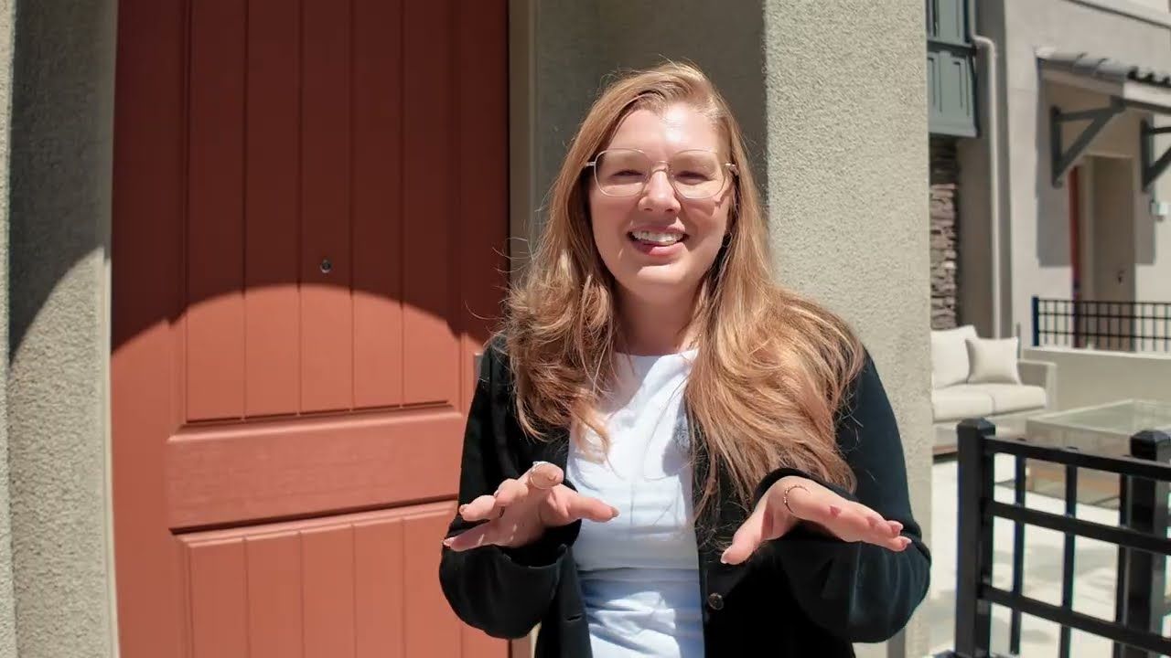 Jessica Heredia at the arched orange entry door of a new construction townhome in Mountain View, CA