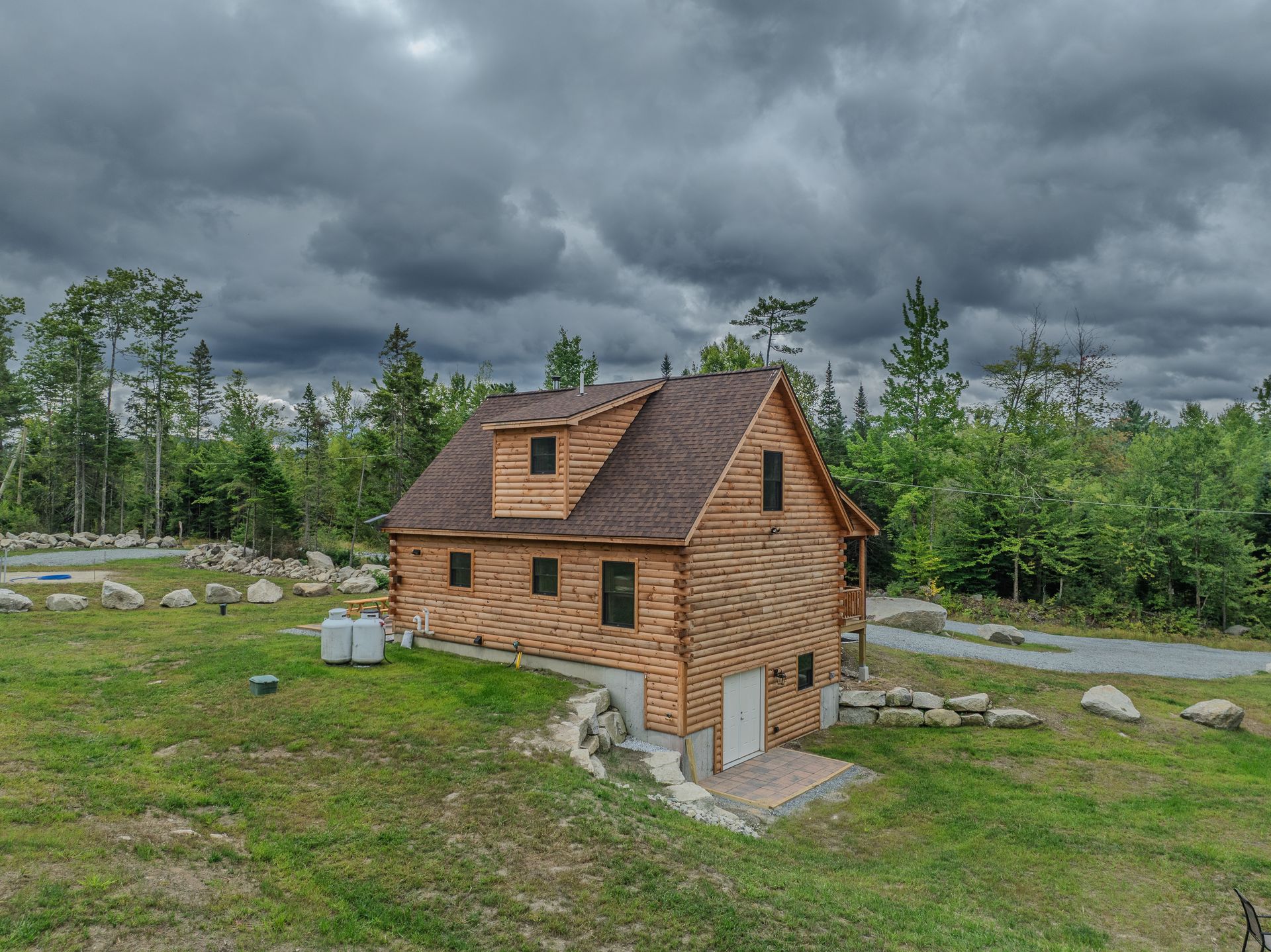 Wooden house with brown roof, green grass, and overcast sky.