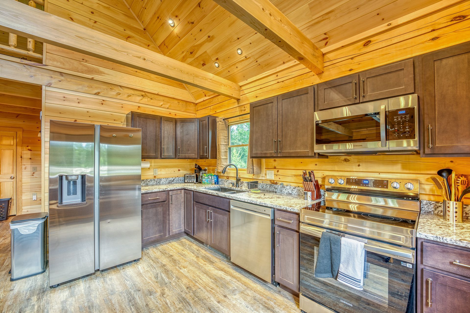 Kitchen with stainless steel appliances, brown cabinets, and wooden walls and ceiling.