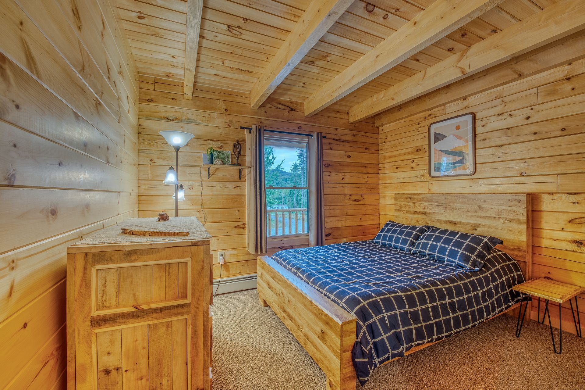 Bedroom with wood paneling, a bed, dresser, and doorway leading outside.