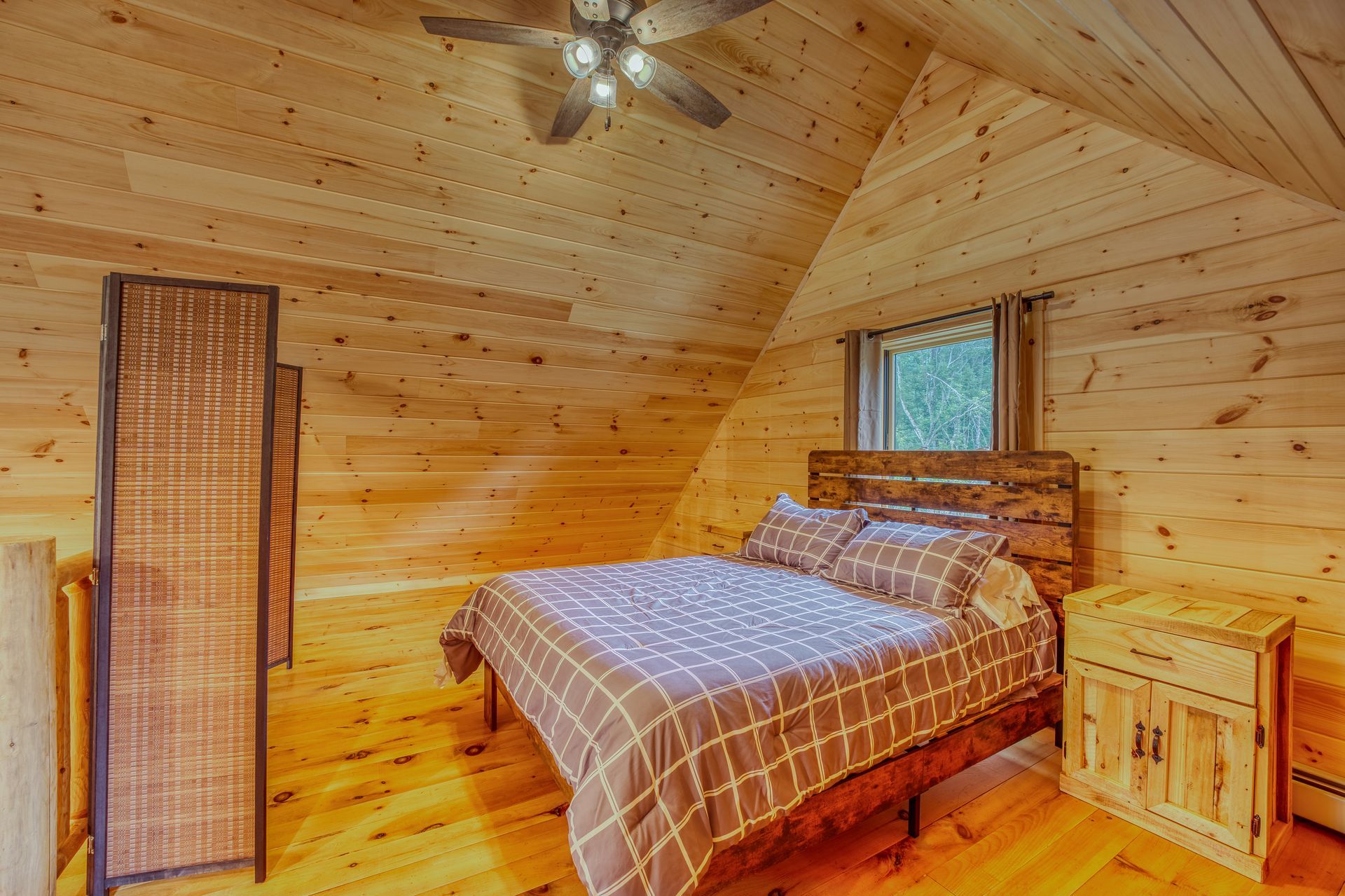 Bedroom with wood paneling, bed, nightstand, and folding screen.