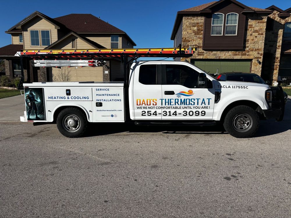 White Thermostat service truck parked in front of a house, with a ladder on top and company logo on the side.