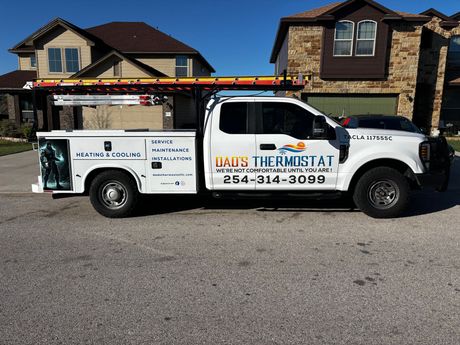White Thermostat service truck parked in front of a house, with a ladder on top and company logo on the side.