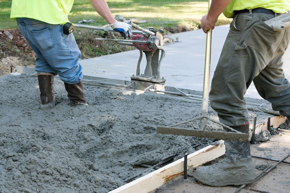 Two Construction Workers Are Working On A Concrete Driveway — Macquarie Valley Rock & Sand In Narromine, NSW