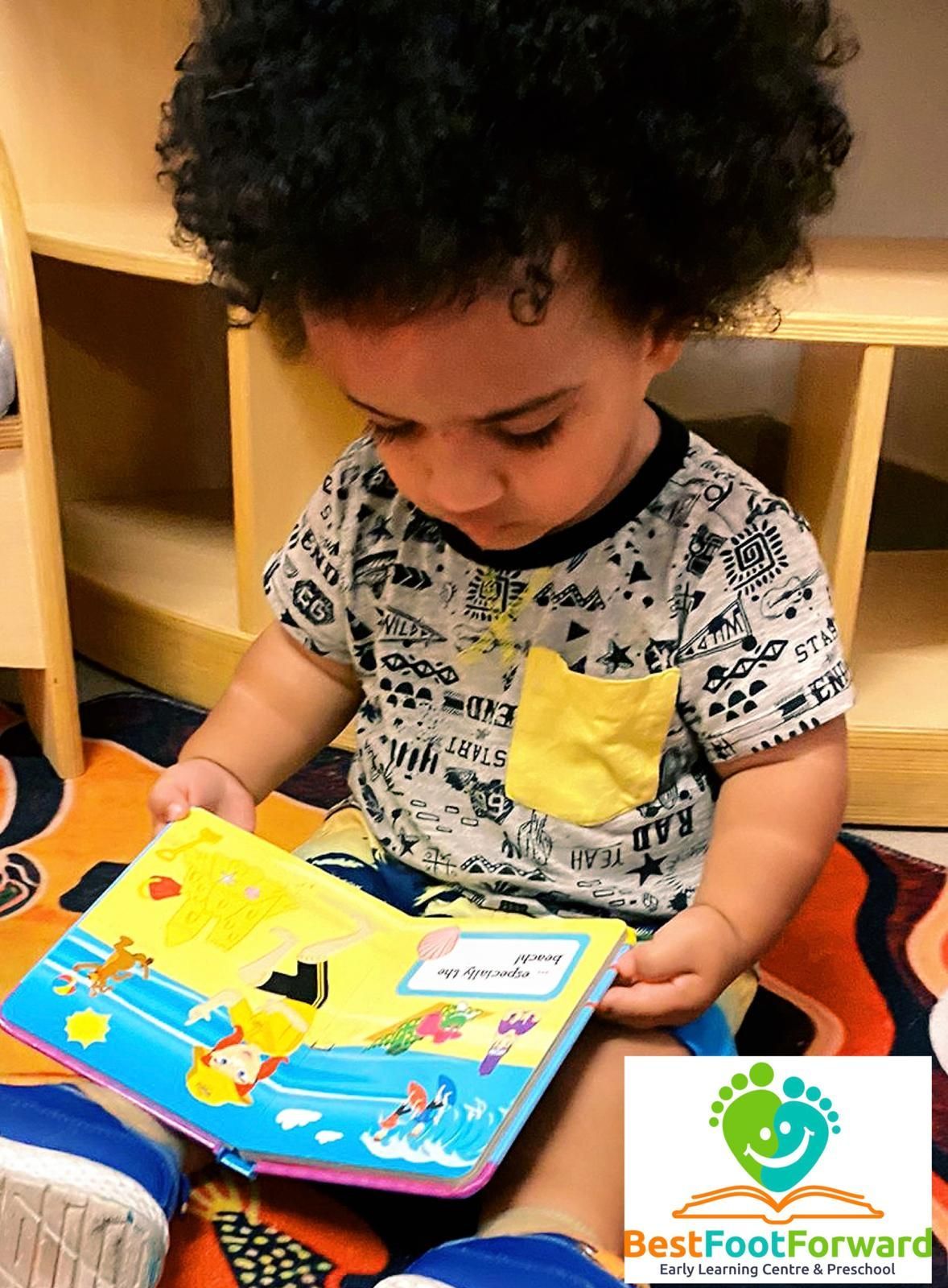 Child reading a colorful picture book while seated on the floor in a bookshelf nook