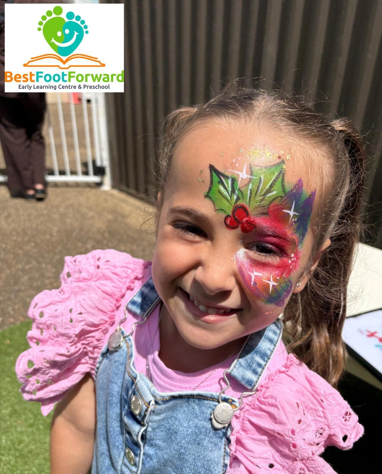 Smiling child with colorful butterfly face paint and pink ruffled shirt outdoors