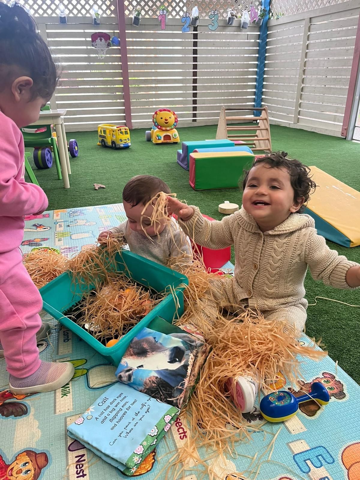 Children playing with toys and sensory bins in a bright indoor play area