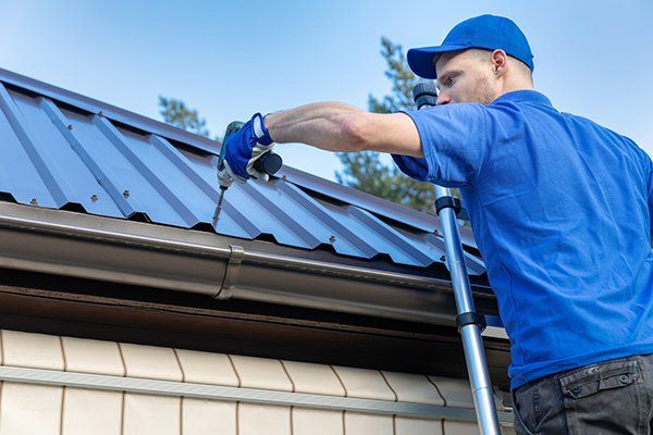 Roofer Working on Metal House Roof — Pittsfield, MA — R & T Roofing A professional doing commercial roof replacement in Lanesborough, MA