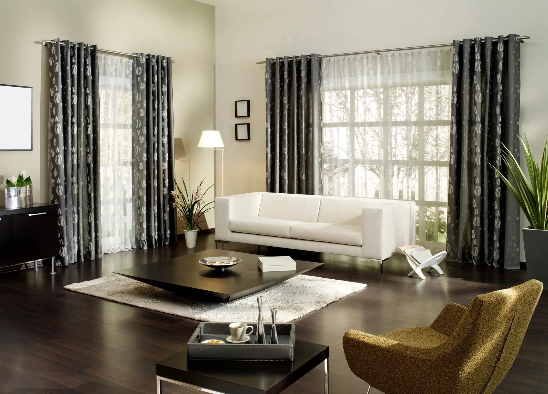 Living room with white sofa, patterned curtains, dark wood floor, and modern furniture.