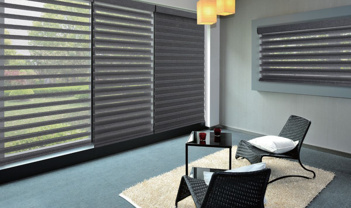 Room with layered horizontal window blinds, two chairs, table, and rug.