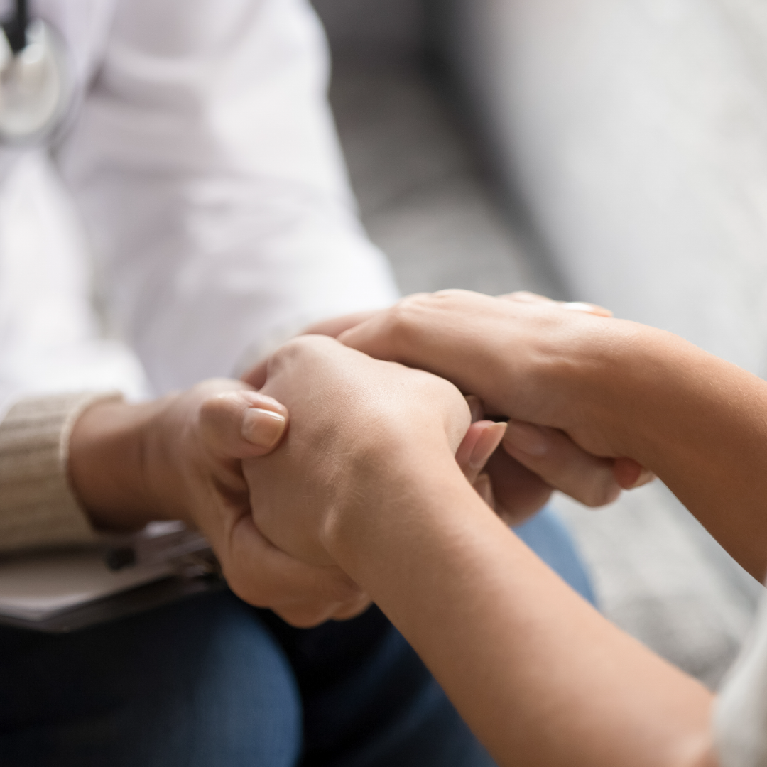 Pregnancy care advocate holding a woman’s hands to offer emotional support during a clinic visit