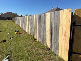 Backyard with a long wooden privacy fence and a lawn mower on a grassy lawn