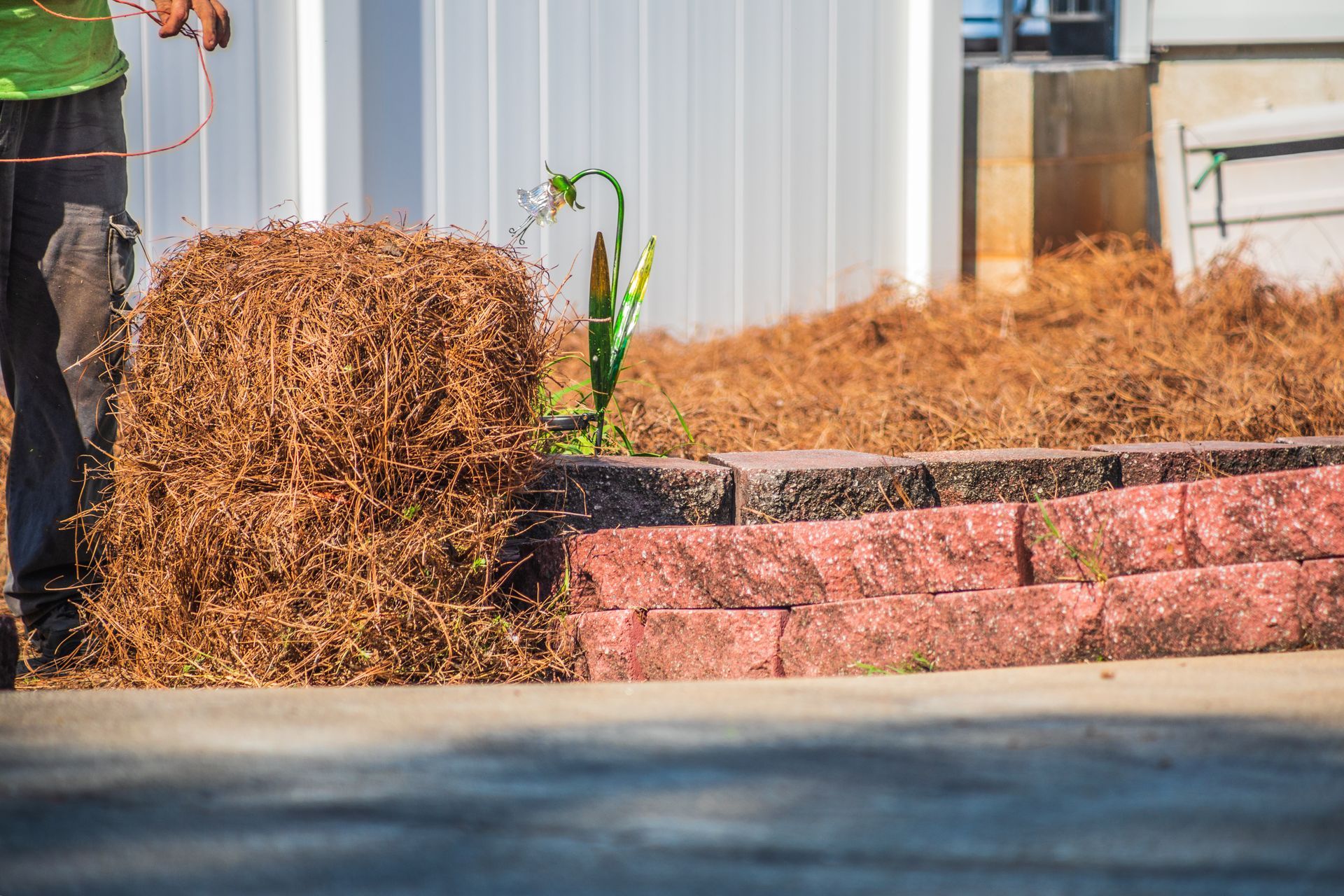Fresh mulch piled beside a pink stone retaining wall outside a building