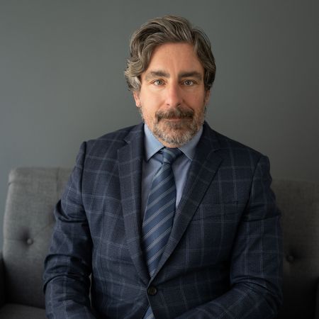 A man in a suit and tie is sitting on a couch.
