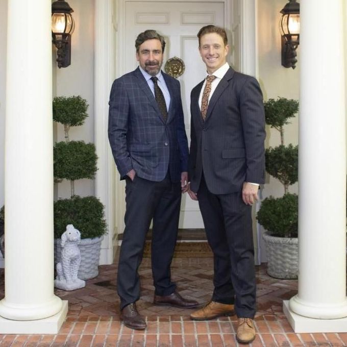 Two men in suits are standing in front of a door