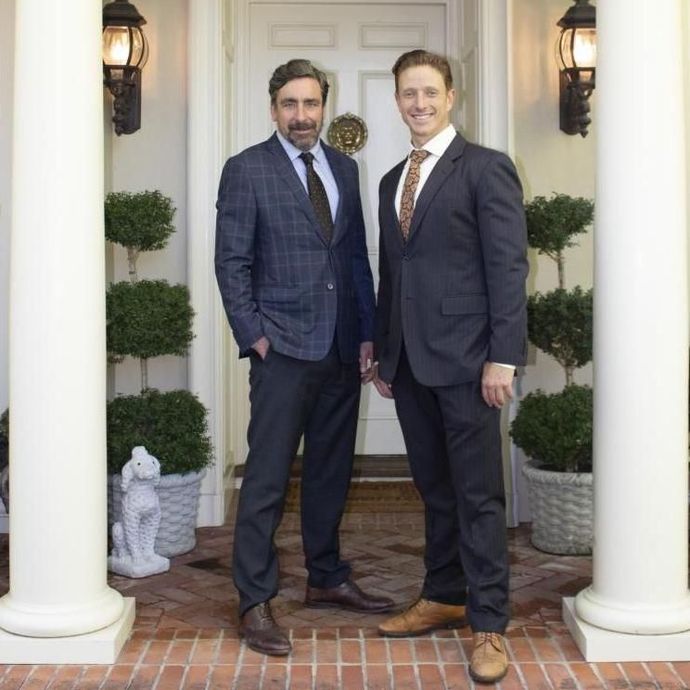 Two men in suits are standing in front of a door