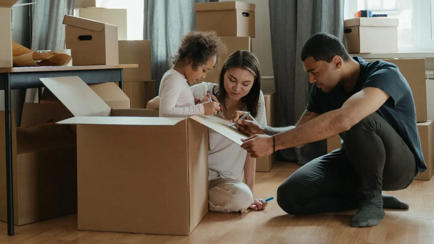 A family is moving into a new home and playing in cardboard boxes.
