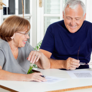 Two people smiling and signing papers at a table in a bright room