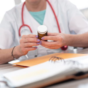 Doctor holding a pill bottle at a desk with a stethoscope and open notebook