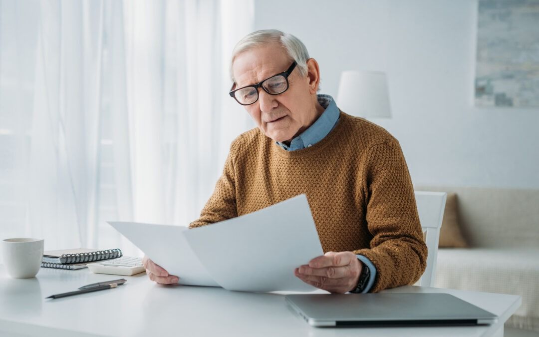 Man sitting at a table reading a document in a bright living room