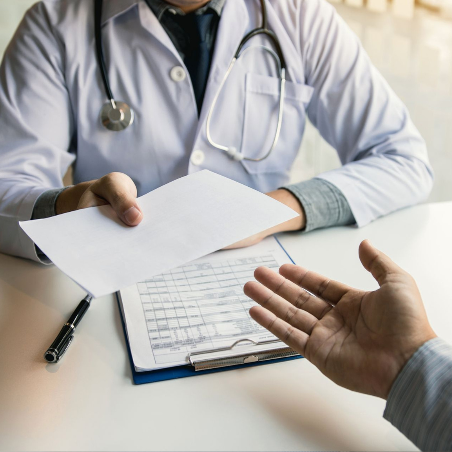 Doctor handing a prescription at a clinic desk, with a pill bottle nearby