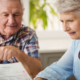 Two people reviewing paperwork together at a table, one pointing at a document.