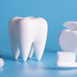 White tooth-shaped object with dental floss and toothpaste on a blue background