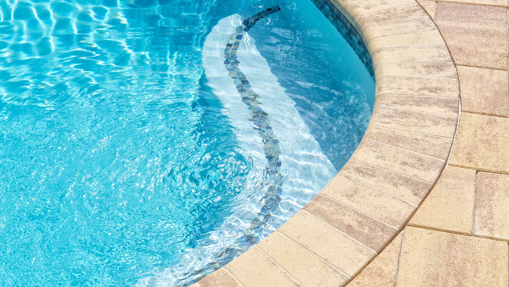 the edge of a swimming pool with a brick border