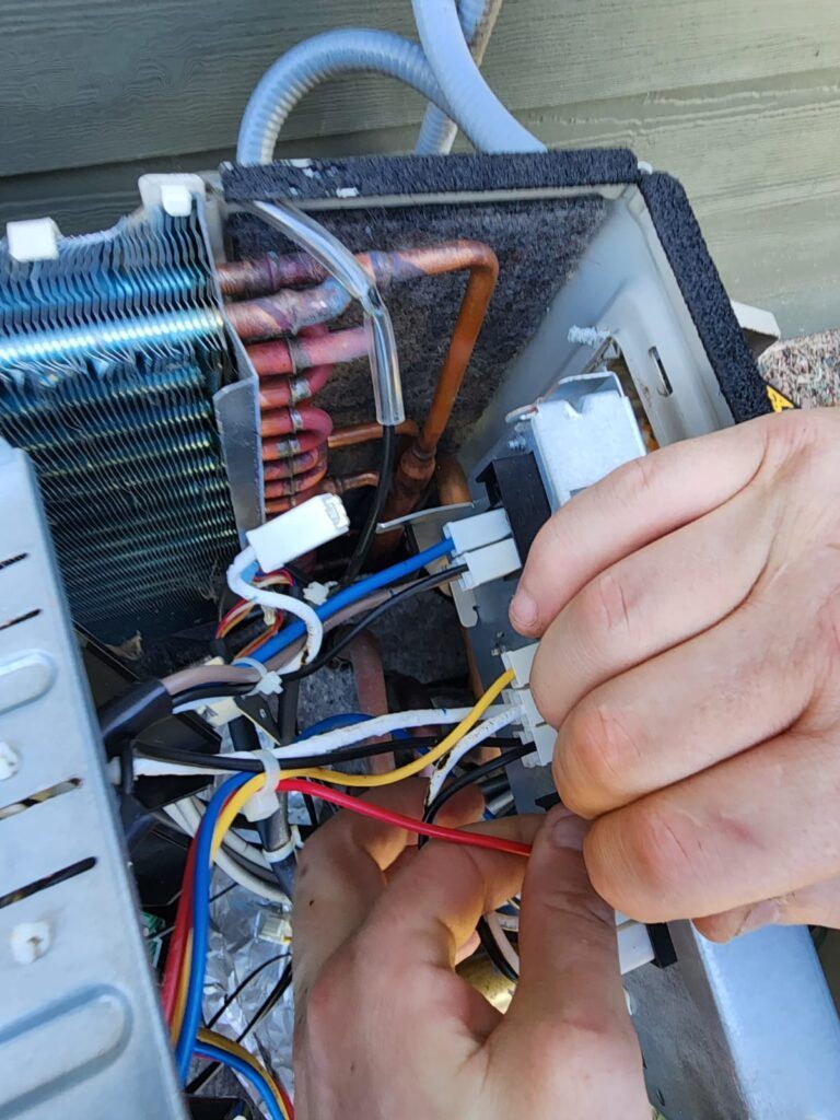 A person is working on an air conditioner with a screwdriver