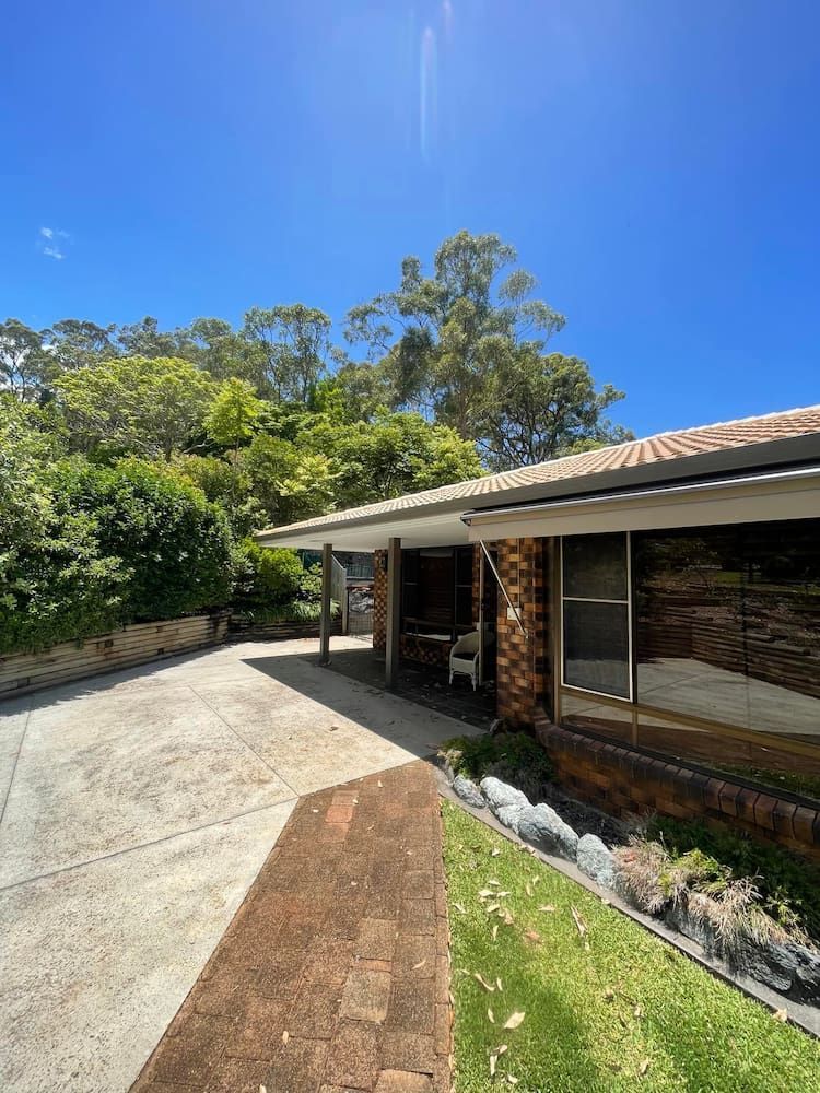 A House With a Driveway and Trees in the Background on a Sunny Day — Cornall Painting Services in Laurieton, NSW
