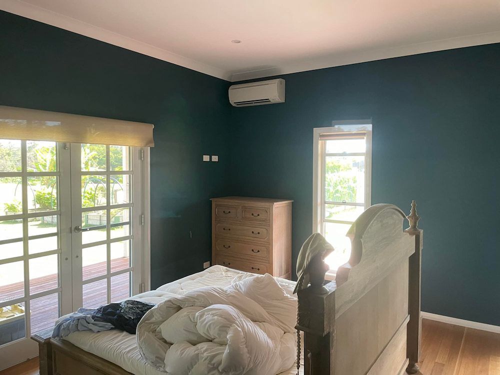 A Bedroom With a Bed, Dresser, and Two Windows — Cornall Painting Services in Wauchope, NSW