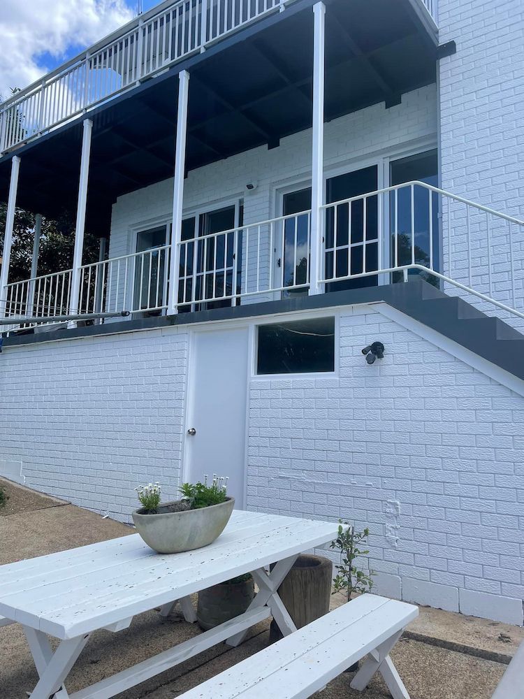 A White Picnic Table and Benches in Front of a White Brick Building — Cornall Painting Services in Wauchope, NSW