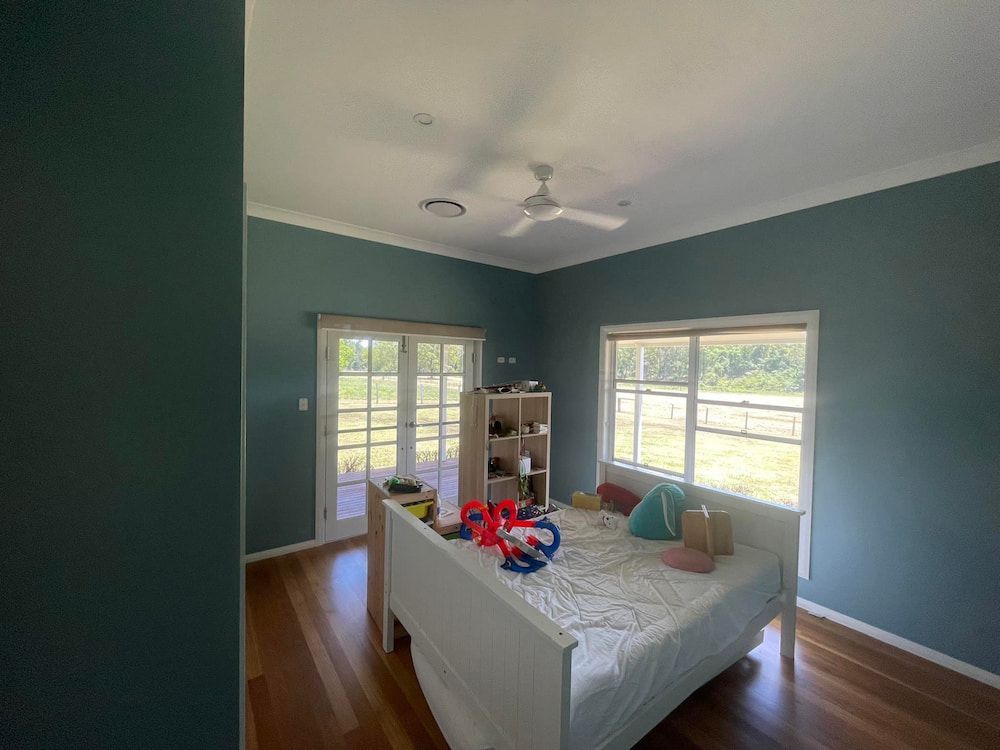 A Bedroom With a Bed and a Ceiling Fan — Cornall Painting Services in Port Macquarie, NSW