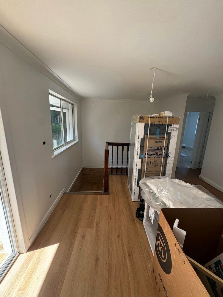 A Hallway With Hardwood Floors and a Staircase in a House — Cornall Painting Services in Wauchope, NSW