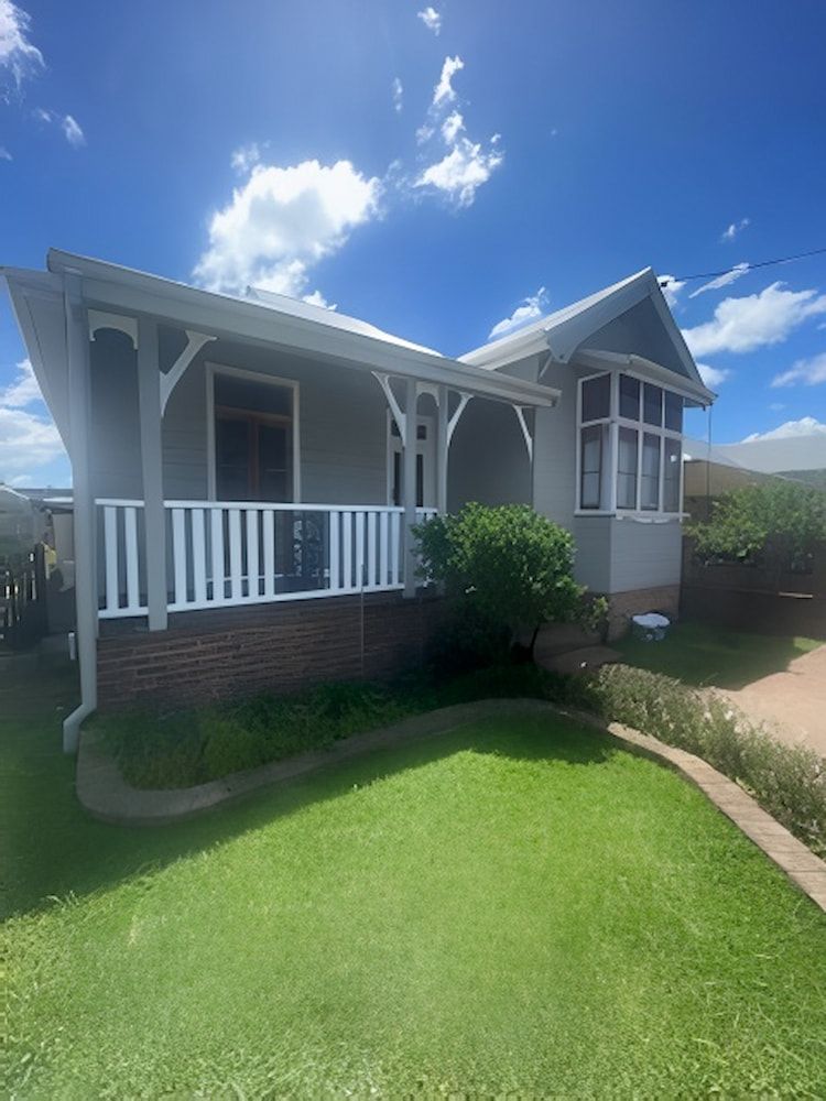 A White House With a Porch and a Blue Sky in the Background — Cornall Painting Services in Port Macquarie, NSW