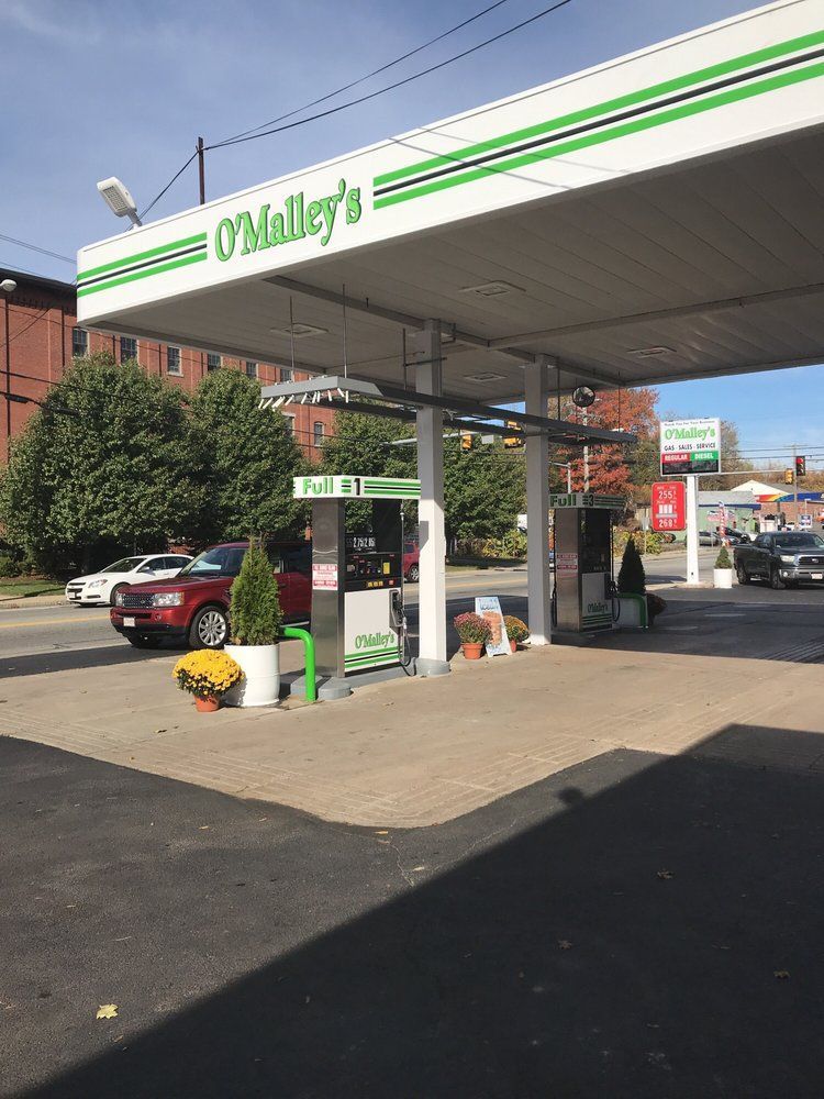 Gas station under a white and green canopy; red SUV filling up at the pump.