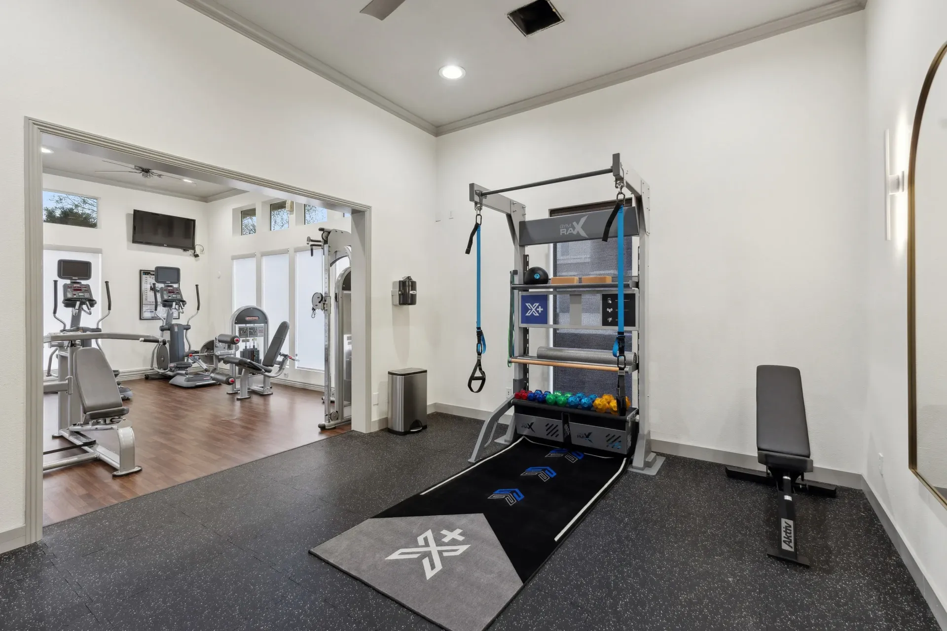 Interior view of a modern gym with cardio machines and a weight rack at Cross Pointe apartments in Antioch, CA.